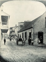 Half of a stereoview showing children in the doorway of the Benet Store and a man on a horse-drawn cart out front, from the intersection of St. George Street and Cuna Street, looking Southwest, ca. 1886[?]