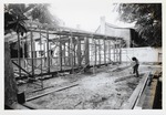 Constructing the Peso de Burgo House, framing the structure and showing a man shaping a beam with an adz, view from the rear yard looking Northwest, 1973