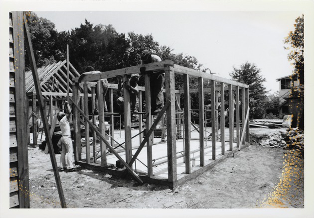 A team of workers constructing the frame of the South outbuilding behind the Peso de Burgo House, looking Northeast, 1973