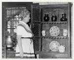 A Woman in Spanish colonial dress in the kitchen of the De Mesa Sanchez House, ca. 1970