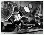 Man in period dress examines a phonograph in the Old Store Museum, ca. 1965
