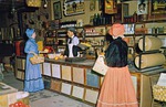 Postcard showing re-enactors in period dress at the counter in the Old Store Museum, ca. 1965
