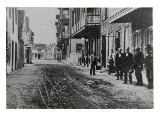 Charlotte Street from near the intersection with Treasury Street, with a group of men standing in front of the County Courthouse on the right, looking South, ca. 1880