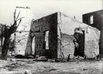 A boy standing in the doorway of the remains of a house on the corner of Charlotte Street and Treasury Street in the aftermath of the fire of 1914, from the rear yard of the house, looking Southeast