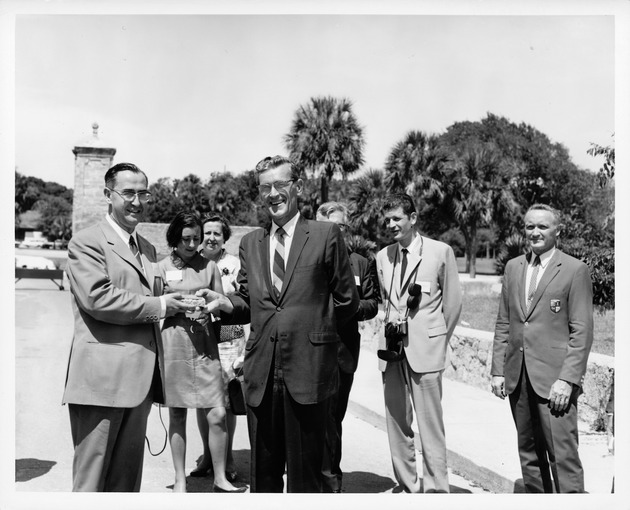 Bradley Brewer presenting a piece of coquina stone to Fernando Suarez, Mayor of Aviles, near the City Gate, looking North, 1969