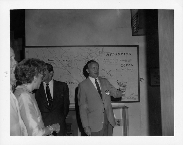 Ambassador Arguelles tours the Florida Heritage House (Wakeman House) - Carl Calkin speaking in front of a map of Florida and the Caribbean Basin