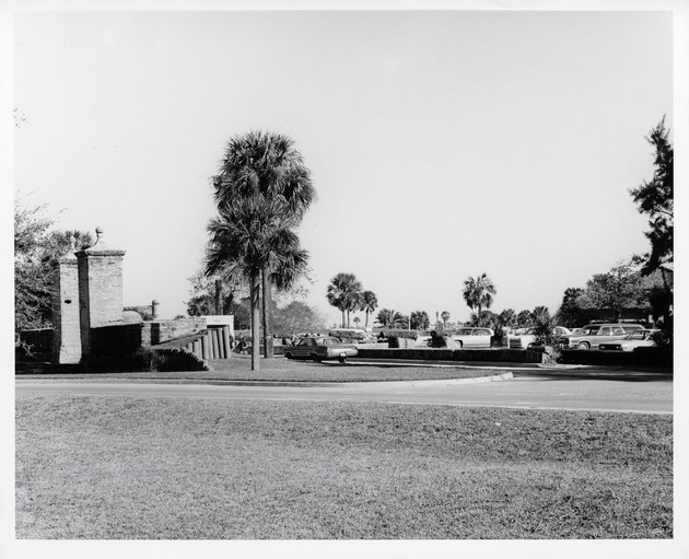The parking lot for the Oldest Wooden School House (Genopoly House) and the City Gate (left), looking East, ca. 1971