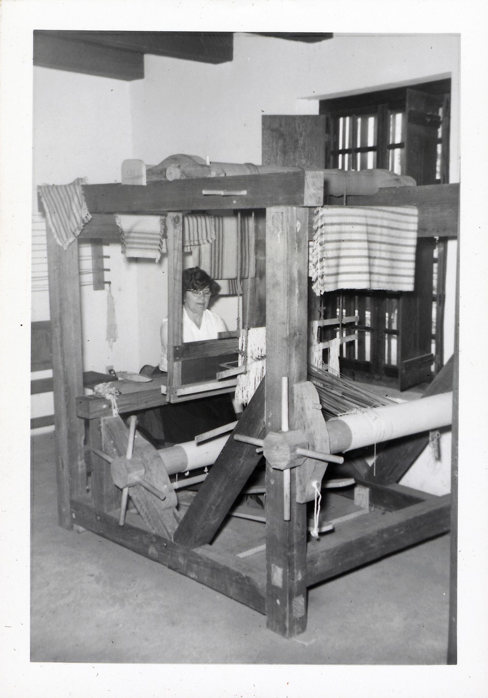 A woman weaving cloth on a loom in Arrivas House