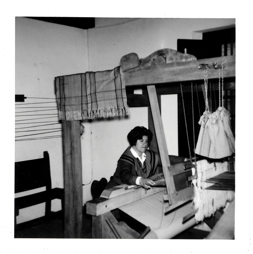 Arrivas House interior with a woman in period clothign weaving on loom