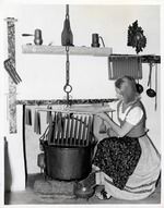A promotional photograph showing a woman in period clothing dipping candles in Arrivas House