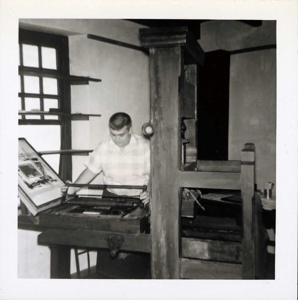 A man operating a historic printing press in the Benet House, 1967