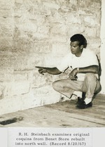Robert H. Steinbach examining original coquina stones rebuilt into the north wall of the Benet Store