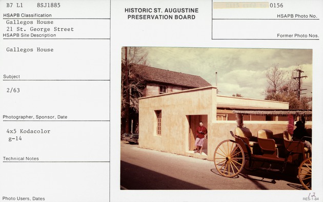 Woman standing at the courtyard entrance to Gallegos House with a carriage on the street